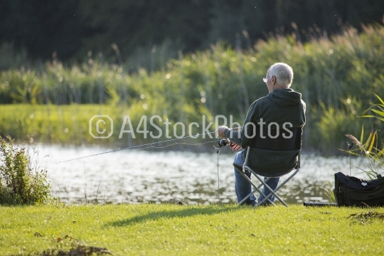 Coarse angler reeling in his bait on the riverbank