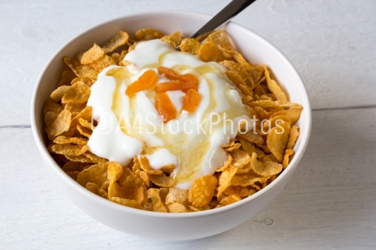 Cornflakes in a bowl with yogurt and honey