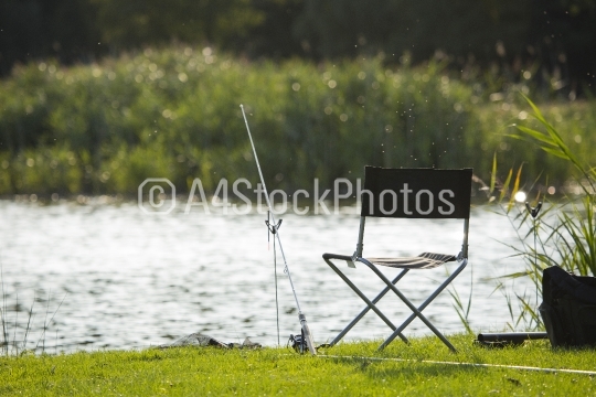 Fishing tackle on the bank, with sunlit water