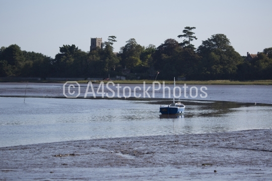 A boat moored in the Alde estuary with Iken church in the backgr