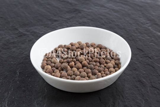 Allspice in a bowl on a slate
