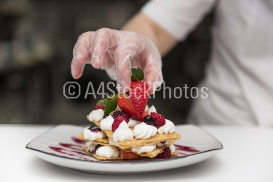 chef putting strawberry dessert