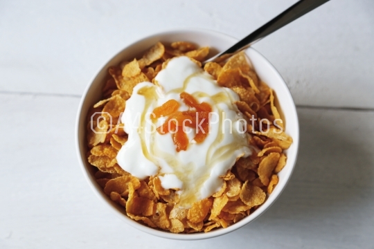Cornflakes in a bowl with yogurt and honey