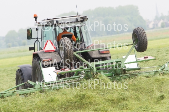 Farmer uses tractor to spread hay on the field