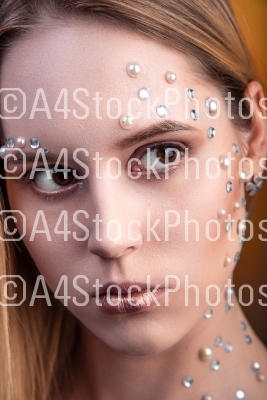 Girl with white and pearl rhinestones on her face.