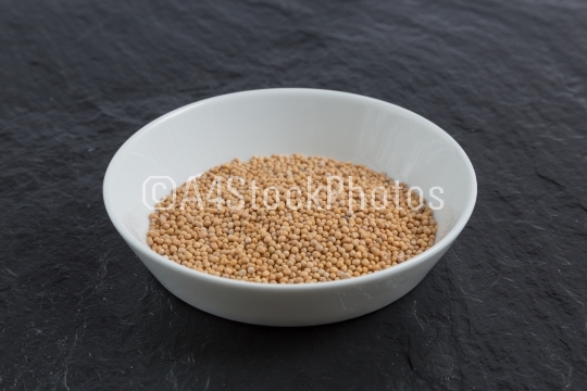 Mustard seeds in a bowl on a slate