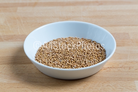 Mustard seeds in a bowl on wood