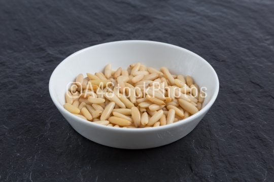 Pine nuts in a bowl on slate