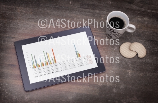 Tablet touch computer gadget on wooden table, graph