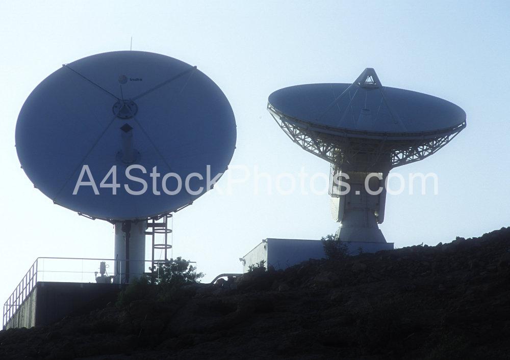 Two satellite dishes silhouetted on a remote hilltop